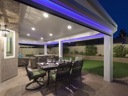 A patio with a table and chairs, lights on the ceiling.