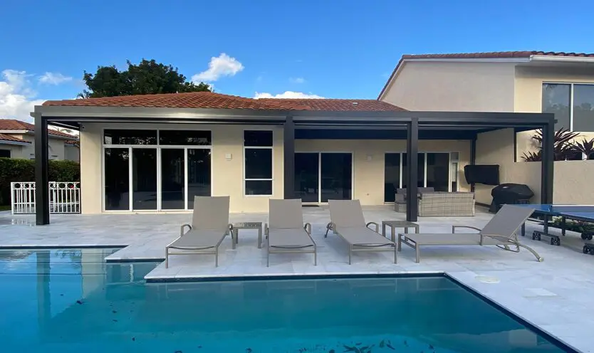 A pool with chairs and tables in the back yard.